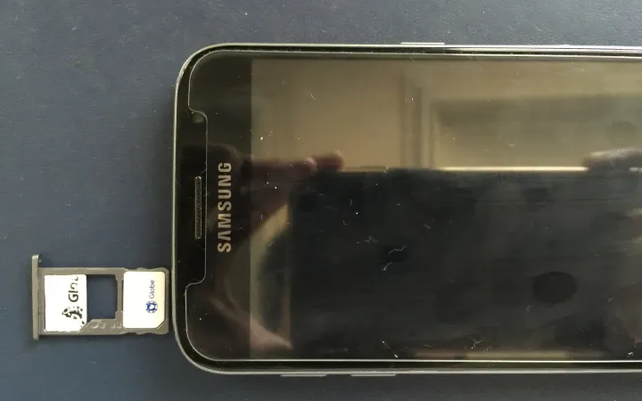 Samsung phone with its dual SIM tray ejected beside it