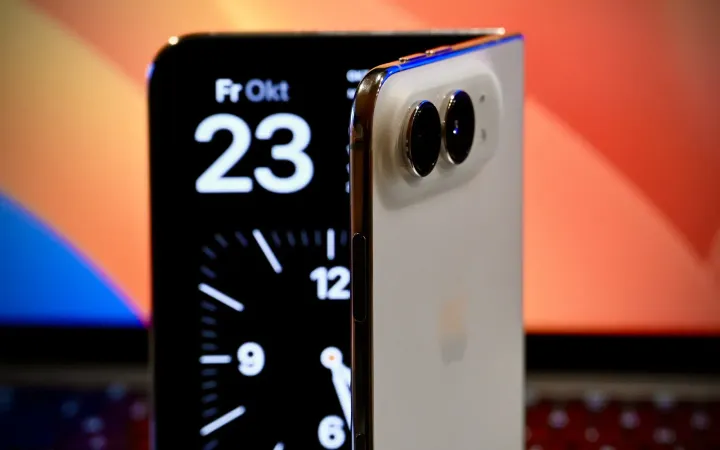 A half-open Apple iPhone Duo foldable in front of a laptop